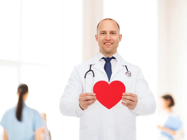 Sorridente médico masculino com coração vermelho e estetoscópio — Fotografia de Stock