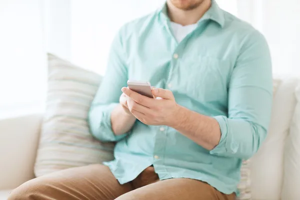 Primer plano del hombre sentado con el teléfono inteligente en casa —  Fotos de Stock