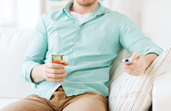 Hombre con cerveza y control remoto en casa — Foto de Stock