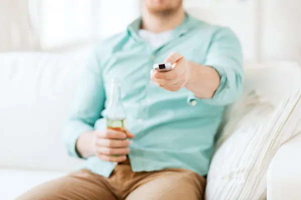 Homem com cerveja e controle remoto em casa — Fotografia de Stock