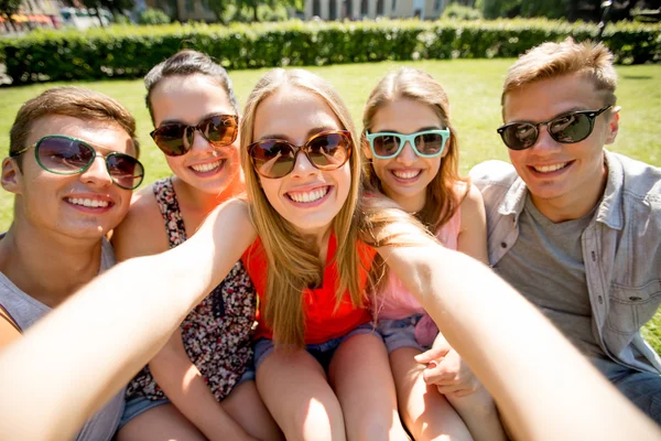 Grupp leende vänner att göra selfie i park — Stockfoto