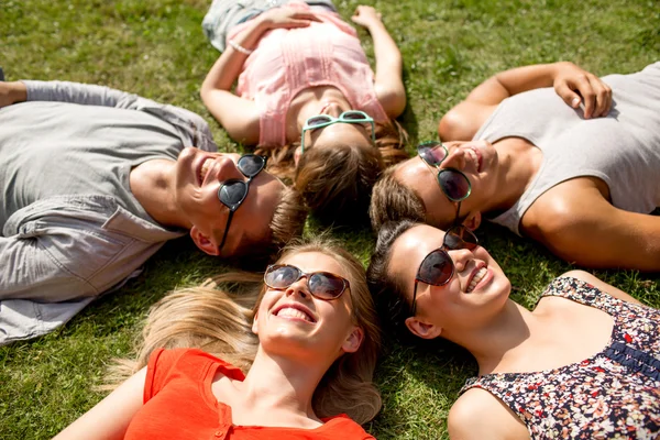 Group of smiling friends lying on grass outdoors — Stock Photo, Image
