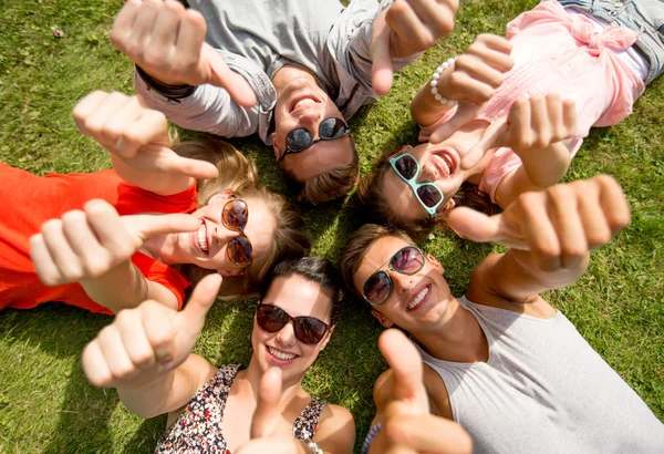 Amis souriants montrant pouces couchés sur l'herbe — Photo