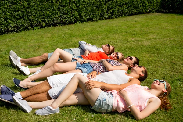 Gruppo di amici sorridenti, sdraiato sull'erba all'aperto — ストック写真