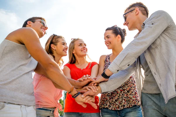 Group of smiling friends with hands on top in city — Stock Photo, Image