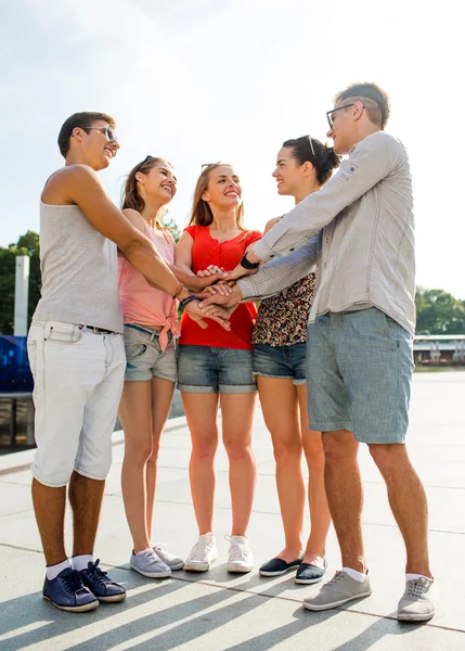 Grupo de amigos sonrientes con manos en la parte superior de la ciudad — Foto de Stock