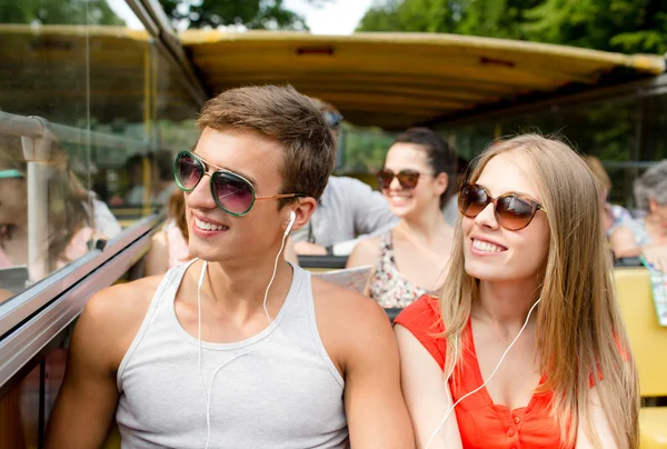 Coppia sorridente con auricolari che viaggiano in autobus — Foto Stock