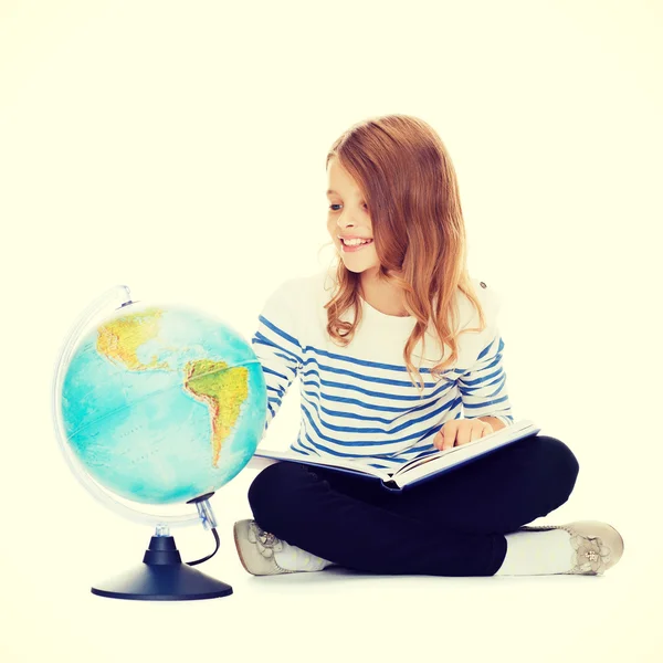Criança olhando globo e segurando livro — Fotografia de Stock