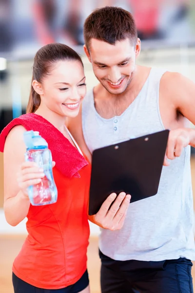 Allenatore maschio sorridente con donna in palestra — Foto Stock