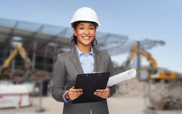 Arquitecto sonriente en casco con plano — Foto de Stock