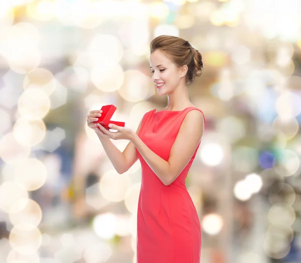 Χαμογελαστή νεαρή γυναίκα με κόκκινο φόρεμα με κουτί δώρου — Φωτογραφία Αρχείου