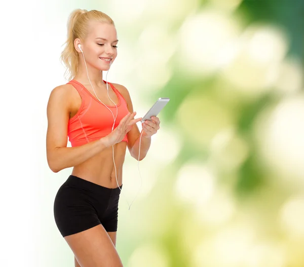 Lachende sportieve vrouw met smartphone en koptelefoon — Stockfoto