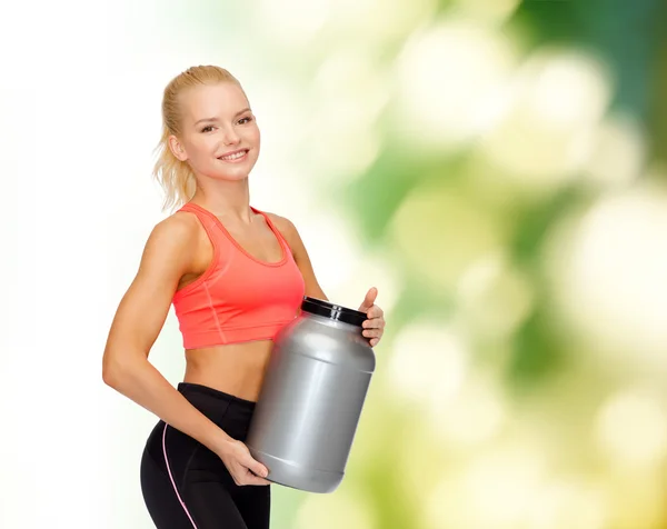 Mujer deportiva sonriente con tarro de proteína —  Fotos de Stock