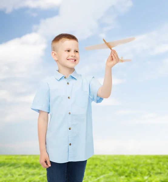 Menino sorrindo segurando um modelo de avião de madeira — Fotografia de Stock