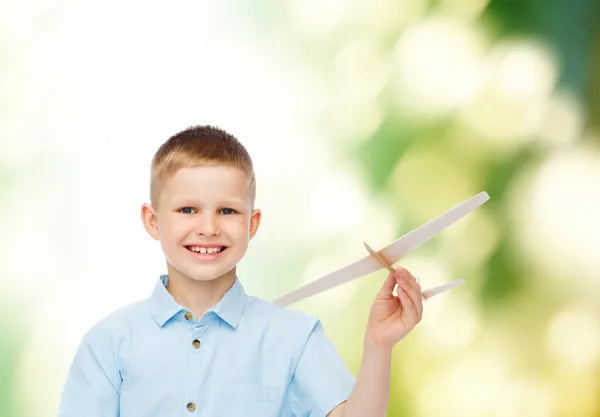 Uśmiechnięty chłopiec trzyma model drewniany samolot — Zdjęcie stockowe