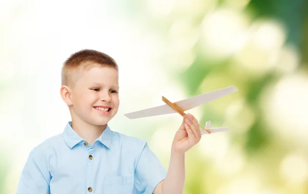 Smiling little boy holding a wooden airplane model — Stock Photo, Image