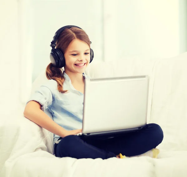 Dizüstü bilgisayar ve evde kulaklık ile kız — Stok fotoğraf