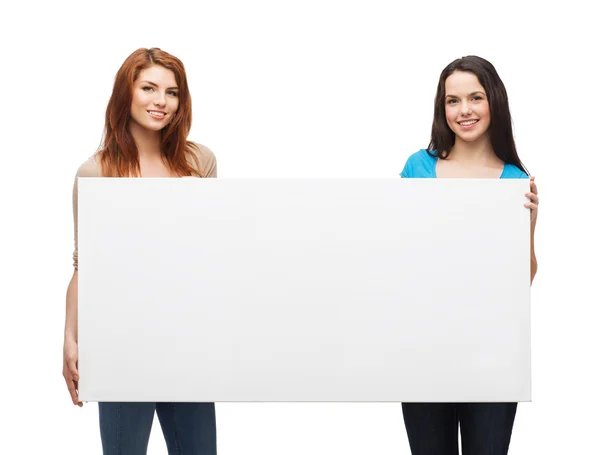 Two smiling young girls with blank white board — Stock Photo, Image