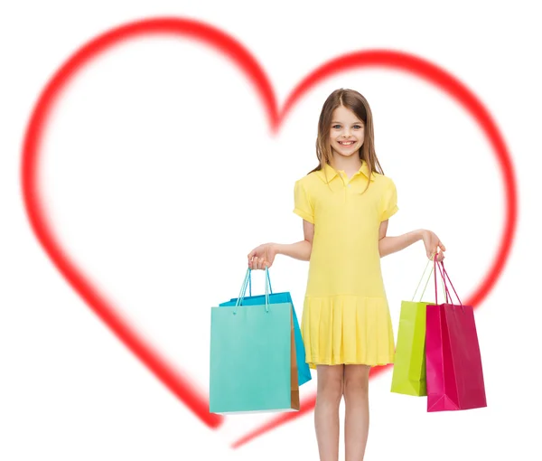 Niña sonriente en vestido con bolsas de compras — Foto de Stock