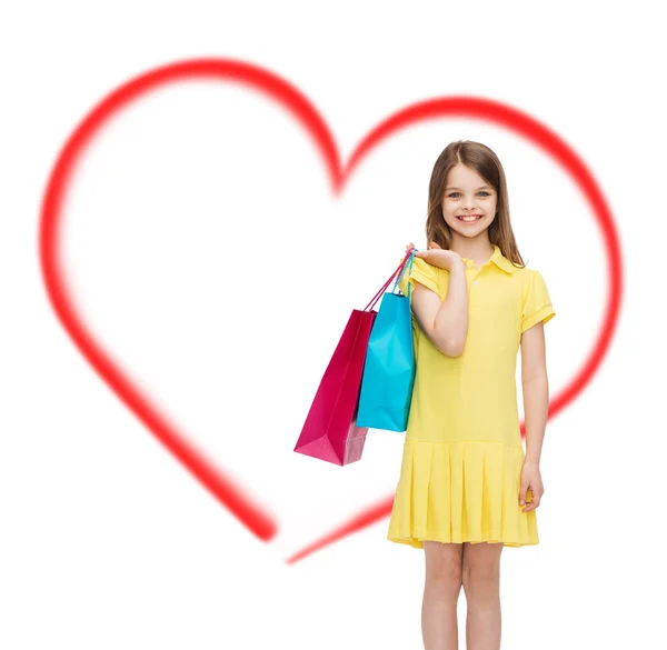 Niña sonriente en vestido con bolsas de compras —  Fotos de Stock