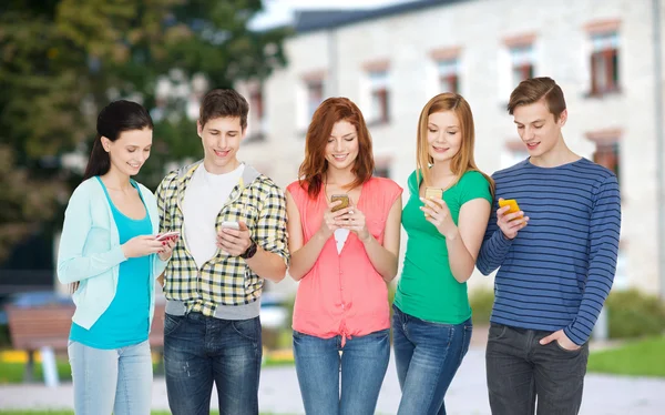 Улыбающиеся студенты со смартфонами — стоковое фото