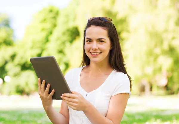 S úsměvem mladá dívka s tablet pc sedí na trávě — Stock fotografie