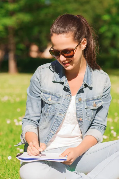 Genç Kız parkta yazılı defter ile gülümseyen — Stok fotoğraf