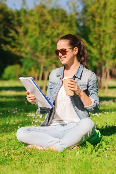 Leende ung flicka med anteckningsboken och kaffe kopp — Stockfoto