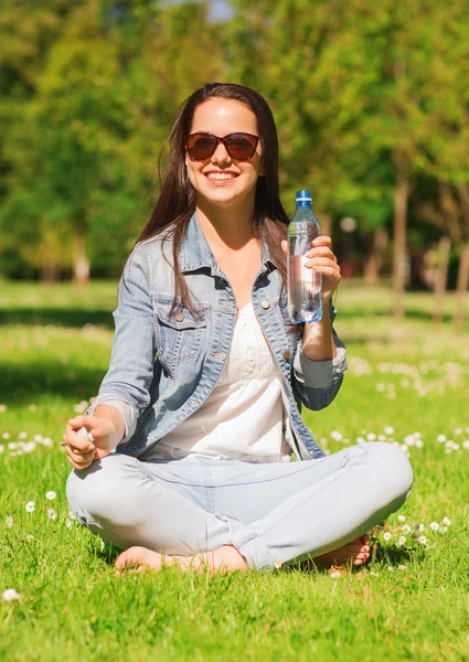 Niña sonriente con botella de agua en el parque — Foto de Stock