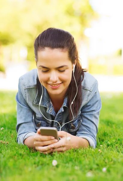 Akıllı telefon ve kulaklık ile gülümseyen genç kız — Stok fotoğraf