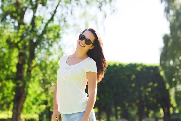 Lachende jonge vrouw met zonnebril in park — Stockfoto