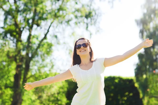 Giovane donna sorridente con occhiali da sole nel parco — Foto Stock