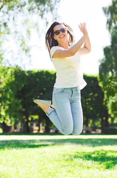 Giovane donna sorridente con occhiali da sole nel parco — Foto Stock