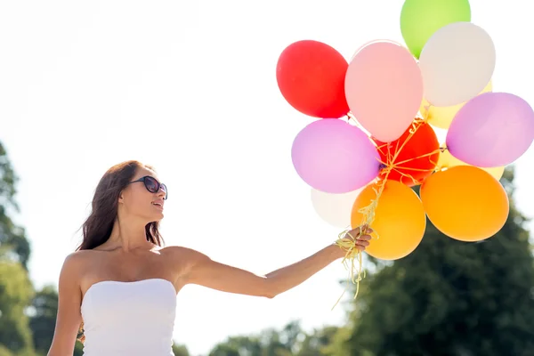 Sorridente giovane donna in occhiali da sole con palloncini — Foto Stock