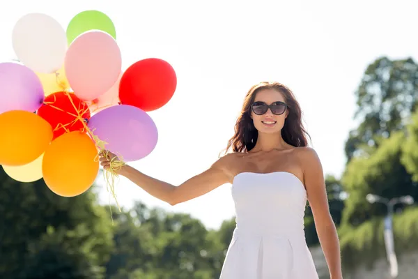 Leende ung kvinna i solglasögon med ballonger — Stockfoto