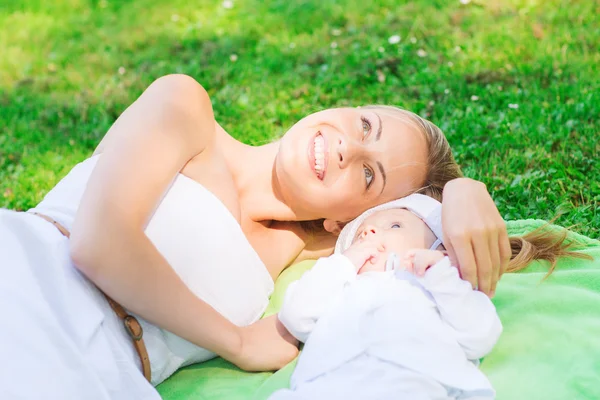 Glad mamma liggande med lilla bebis på filt — Stockfoto