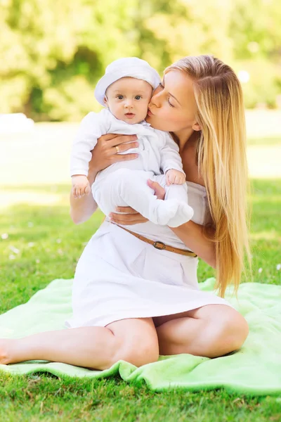 Madre feliz con el pequeño bebé sentado en la manta —  Fotos de Stock