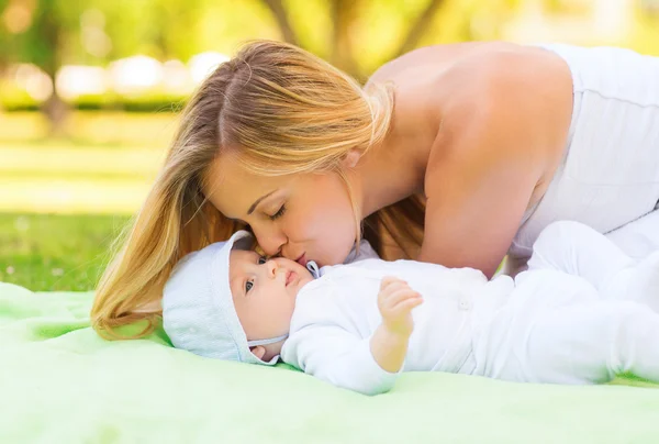 Счастливая мать, лежащая с маленьким ребенком на одеяле — стоковое фото