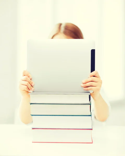Дівчина ховається за планшетом і книгами в школі Ліцензійні Стокові Зображення