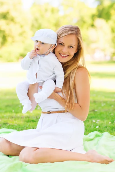 Madre feliz con el pequeño bebé sentado en la manta — Foto de Stock