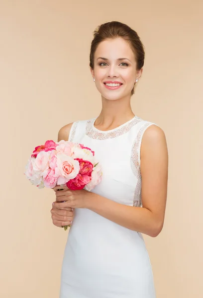 Gül kokulu beyaz elbiseli kadın gülümsüyor — Stok fotoğraf
