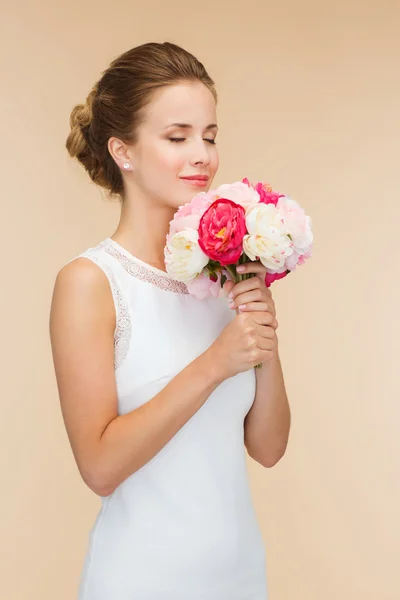 Smiling woman in white dress with bouquet of roses — Stock Photo, Image