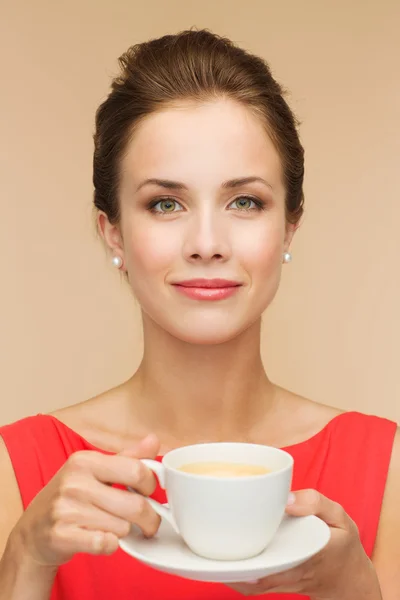 Lachende vrouw in rode jurk met kop koffie — Stockfoto