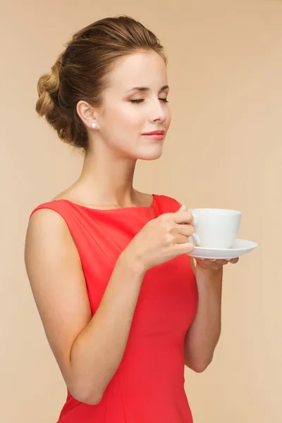 Lachende vrouw in rode jurk met kop koffie — Stockfoto