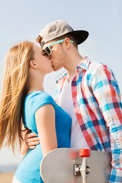 Mosolyogva pár gördeszka csók szabadban — Stock Fotó