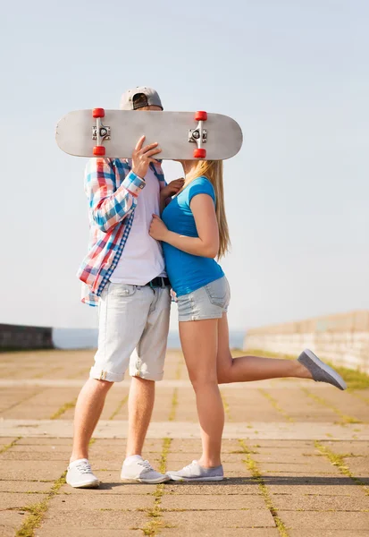 Casal com skate beijando ao ar livre — Fotografia de Stock