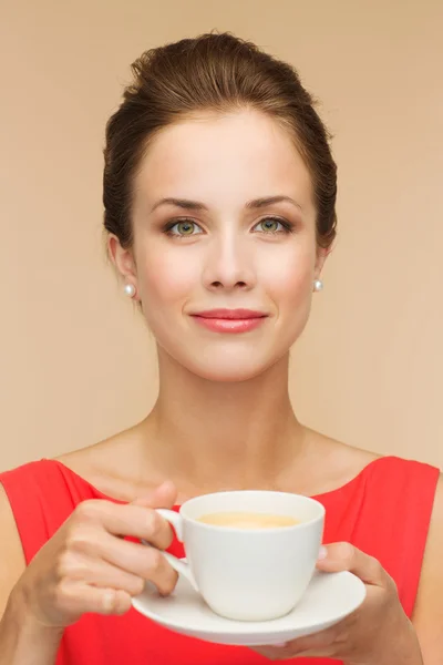 Χαμογελώντας γυναίκας με κόκκινο φόρεμα με καφέ Εικόνα Αρχείου