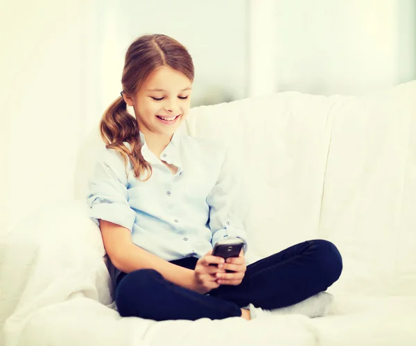 Evde smartphone ile gülümseyen kız — Stok fotoğraf