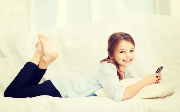 Ragazza sorridente con smartphone a casa — Foto Stock