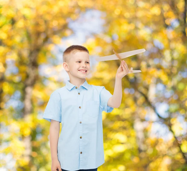 Smiling little boy holding a wooden airplane model — Stock Photo, Image